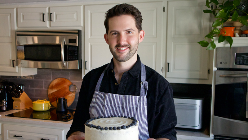 Barrett Radziun holding a decorated cake in a kitchen