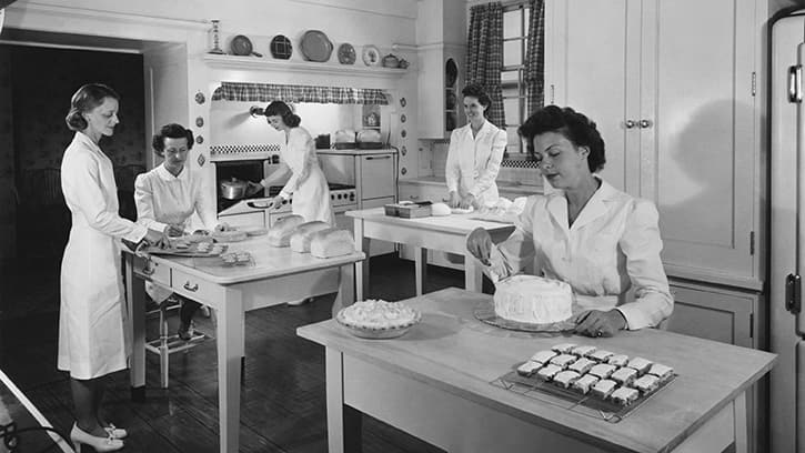 An archival photo in black & white of bakers inside The Betty Crocker Kitchens