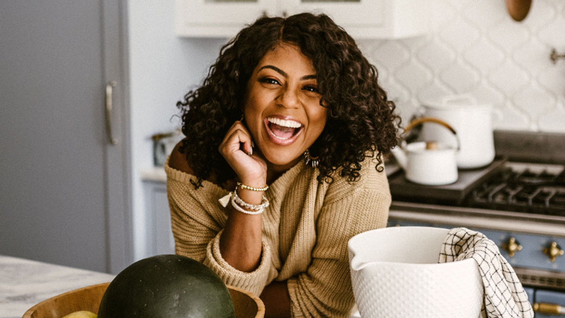 Britney Brown-Chamberlain smiling at the camera and leaning on the countertop in the kitchen 