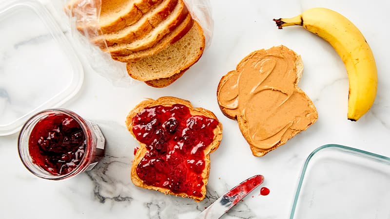 Slices of bread with jam and peanut butter, a whole banana